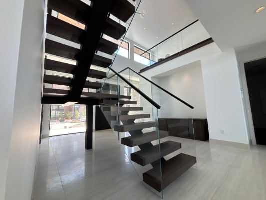 Black stringer and dark floating treads with frameless glass and black top cap on glossy tile floors