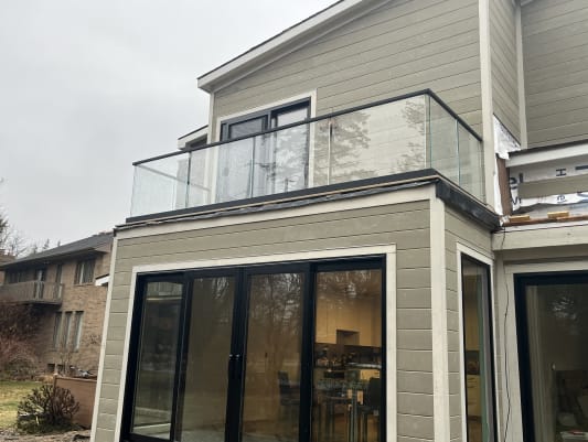 Frameless base rail glass balcony with a black cap on a gray-sided home