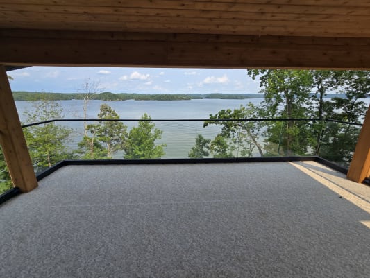 Frameless base rail glass under timber beams frames a sweeping lake and island view