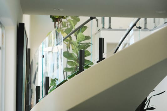 Curved glass panels on black talons with a black handrail sweep along a white curved stair stringer.