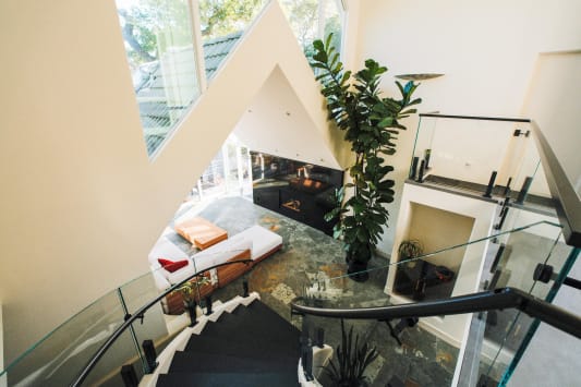 Looking down past curved frameless glass on black talons into a living room with a slate floor.
