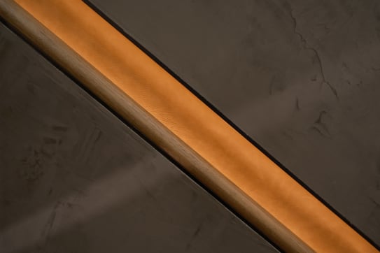 Close view of a wood handrail recessed in a softly lit wall channel.