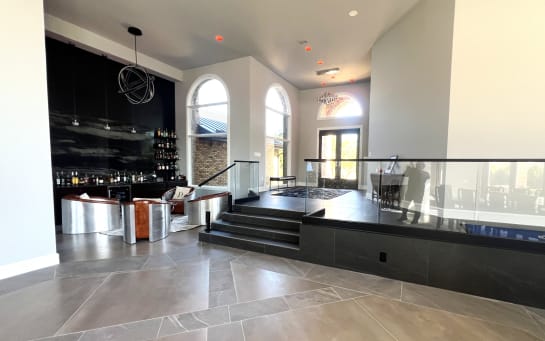 Frameless glass railing on talon spigots wraps a raised platform in a dramatic home bar
