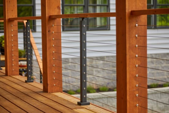Stainless cables with DriveTite fittings run through cedar posts and a black cable post on a wood deck.
