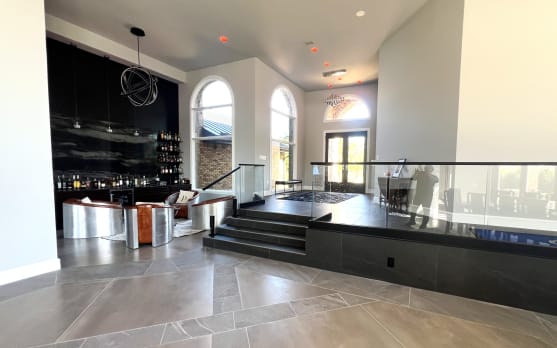 Frameless glass railing on talon spigots wraps a raised platform in a dramatic home bar