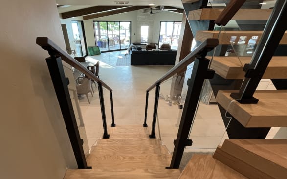Oak floating treads with black-post glass railing and walnut handrail opening to a living room