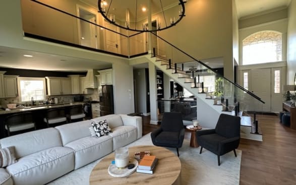 Open-plan living room with a white stair and black-capped glass railing continuing along the upper loft.