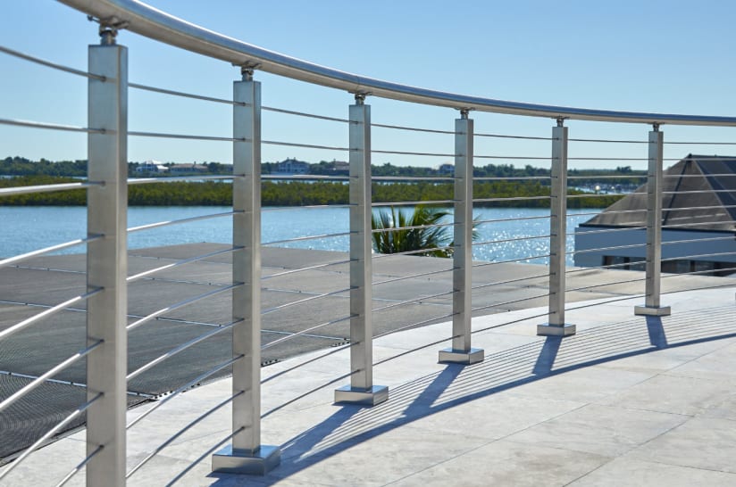 Stainless posts with a curved round handrail and horizontal infill sweep around a terrace by the water.